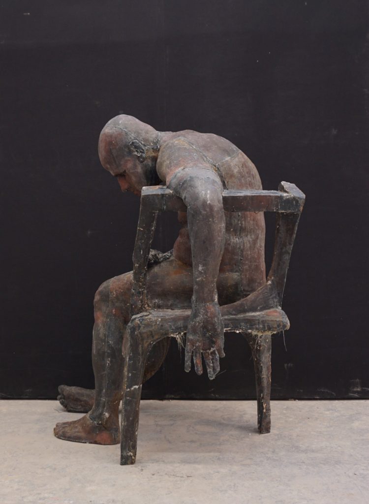 rzeźba zmeczonego człowieka siedzącego na krześle