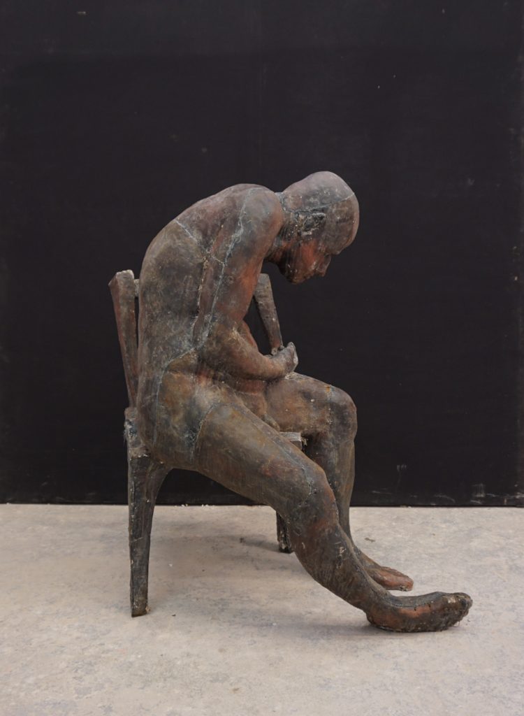 rzeźba zmeczonego człowieka siedzącego na krześle