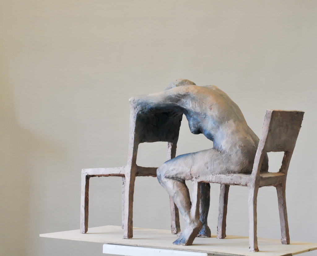 rzeźba kobiety opartej o krzesło