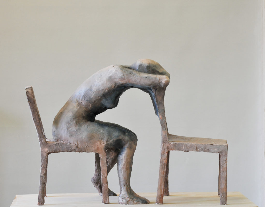 rzeźba kobiety opartej o krzesło