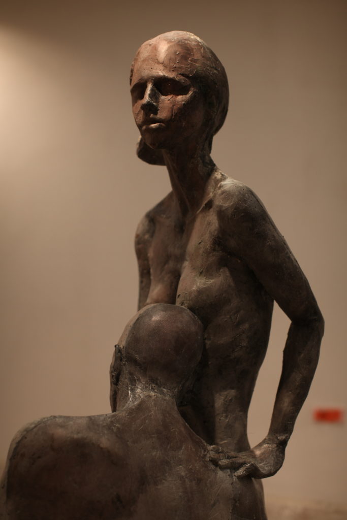 rzeźba mężczyzny opartego w pozycji siedzącej o stojącą kobietę